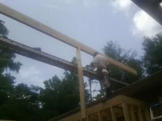Carpenter setting a ridge beam over a new addition frame — Ice Dam Removal by Roofing Brothers in Abercrombie