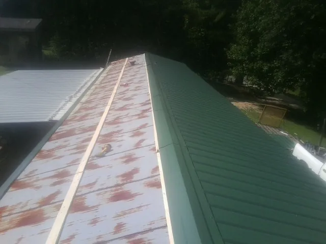 Old rusted panels beside newly installed green metal roofing — Wind Damage Roof Repair by Roofing Brothers in Abercrombie
