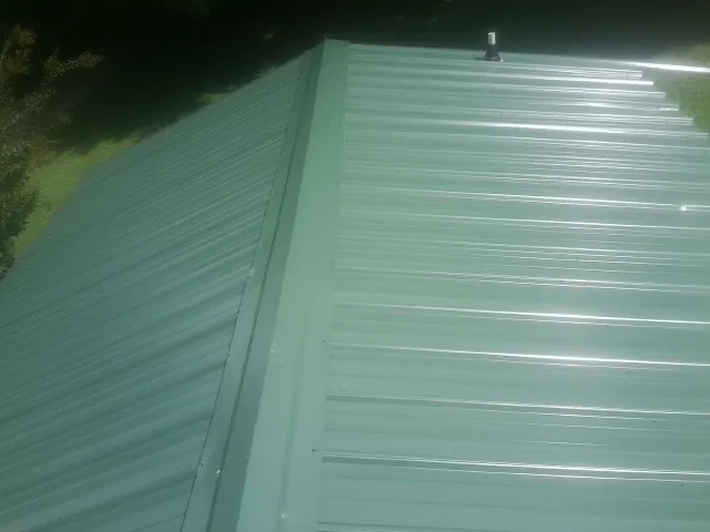 New green metal panels meeting at the ridge of a roof — Flat Roof Repair work by our crew in Abercrombie