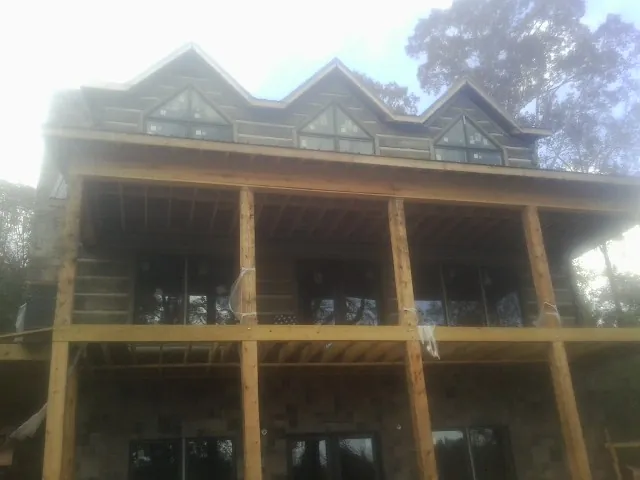 Dormers and porch framing on a large log home under construction — Roof Coating work by our crew in Abercrombie