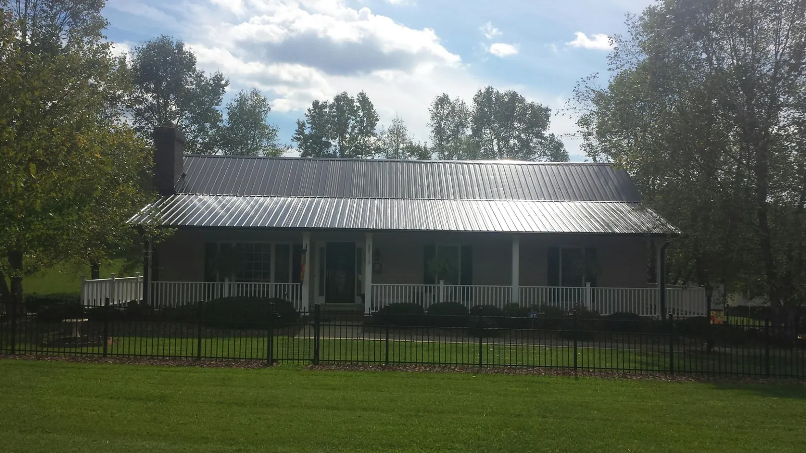 Gray metal roof on a brick ranch with a full width front porch — Gutter Guard Installation work by our crew in Abercrombie