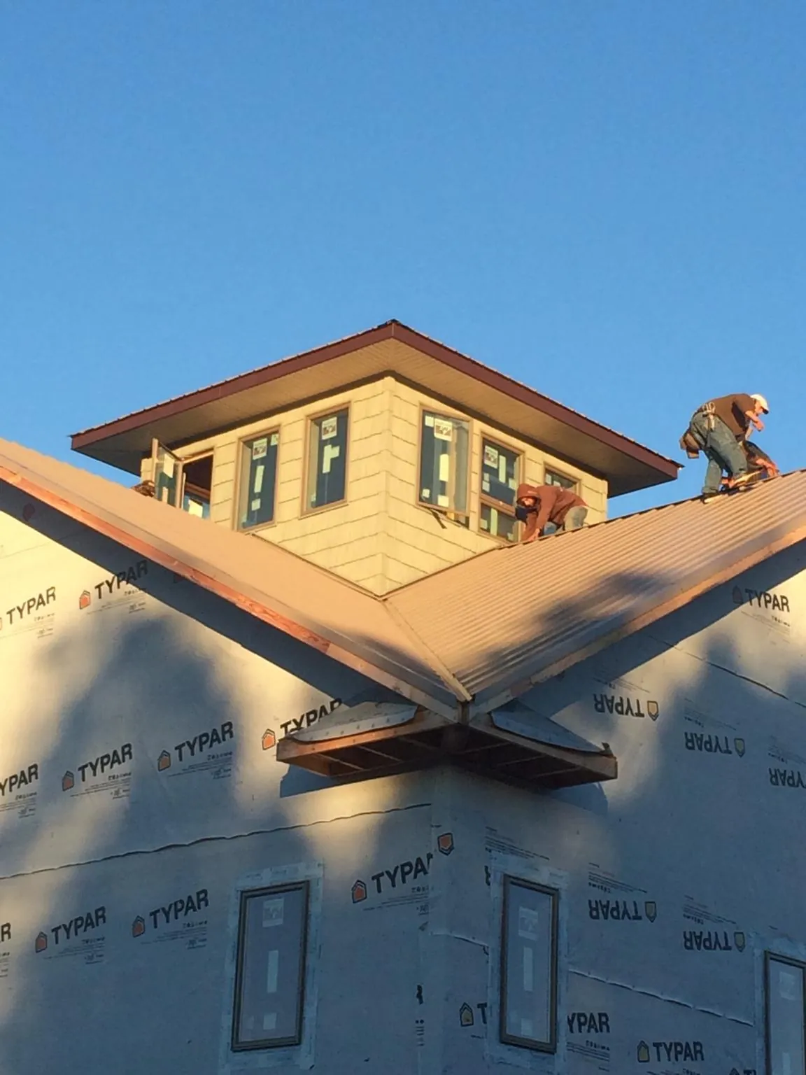 Roofers working around a rooftop cupola on a new metal roof at sunset — Roof Waterproofing in Abercrombie by Roofing Brothers